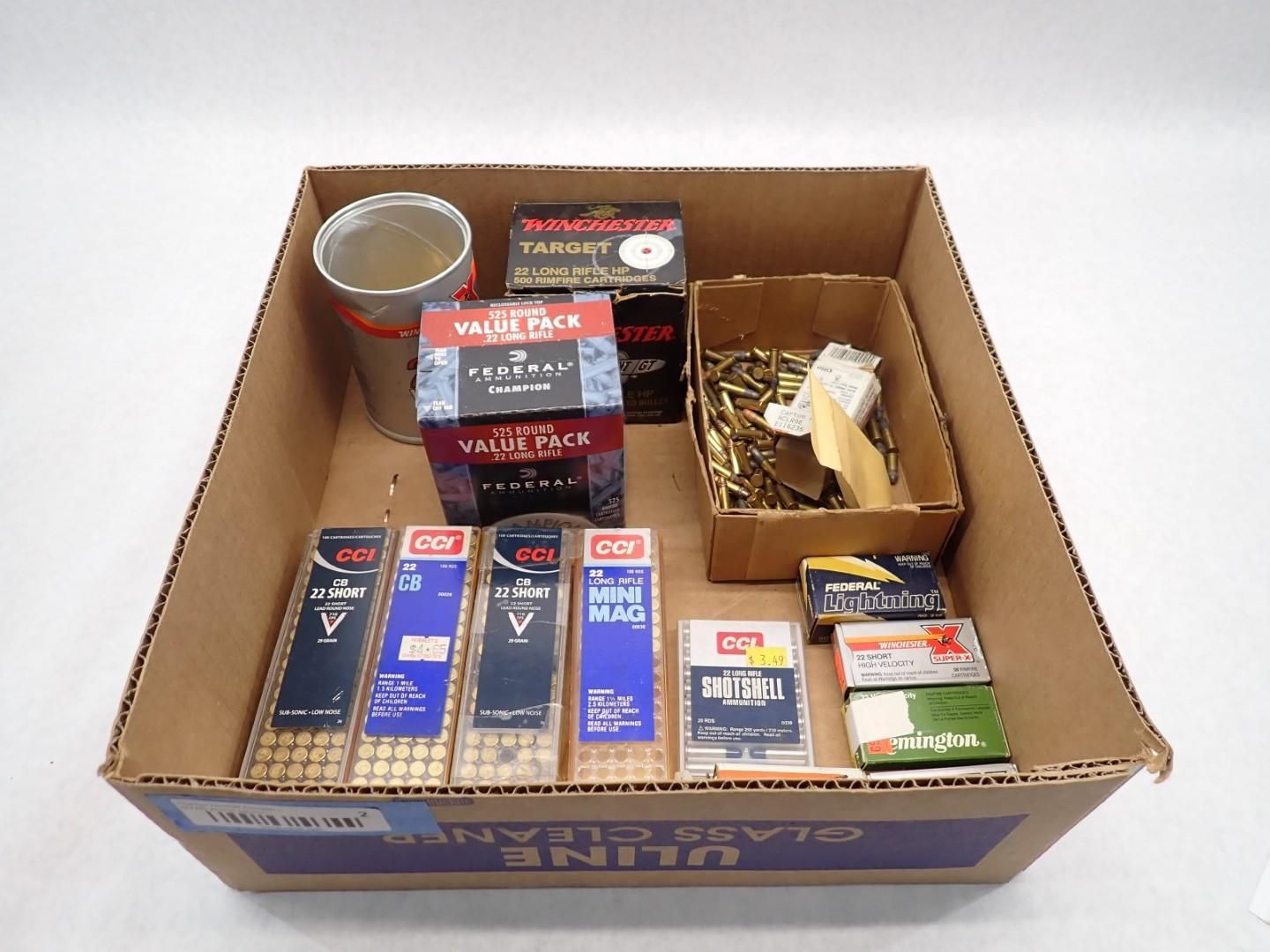 Cardboard box containing various ammunition boxes, brass casings, and a paper container.