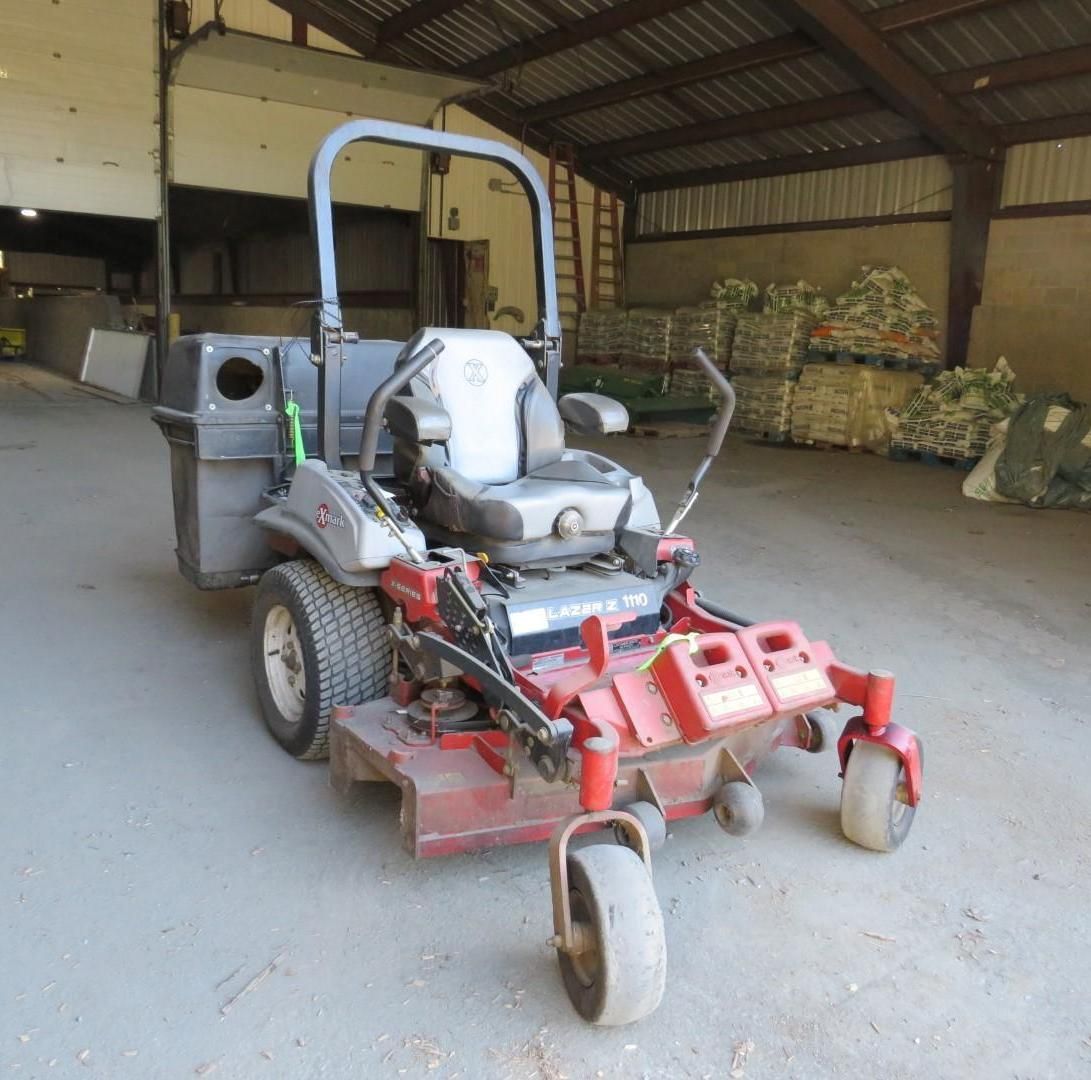 Red and black zero-turn lawnmower parked inside a barn.