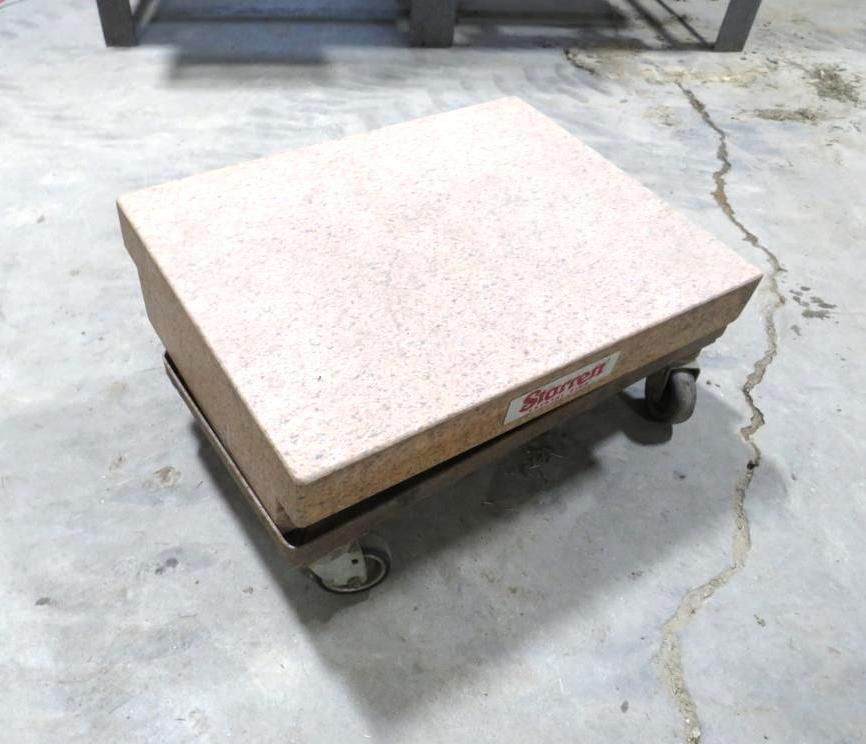 A beige rectangular shop stool with wheels on a concrete floor.