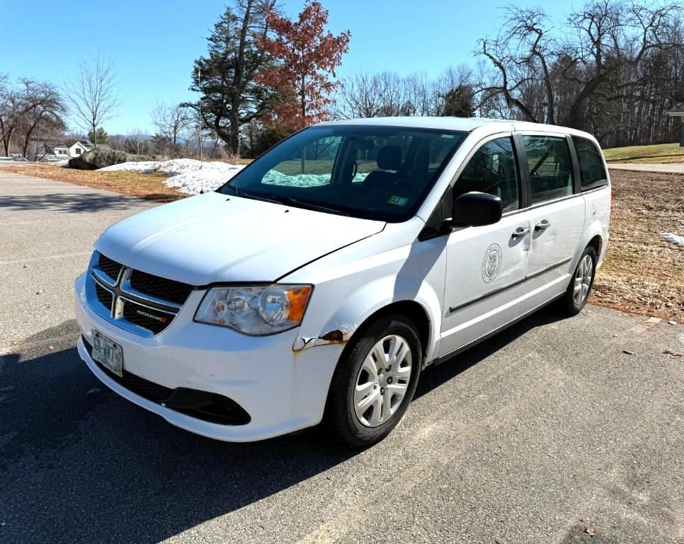 White Dodge Grand Caravan minivan parked on pavement, daylight.