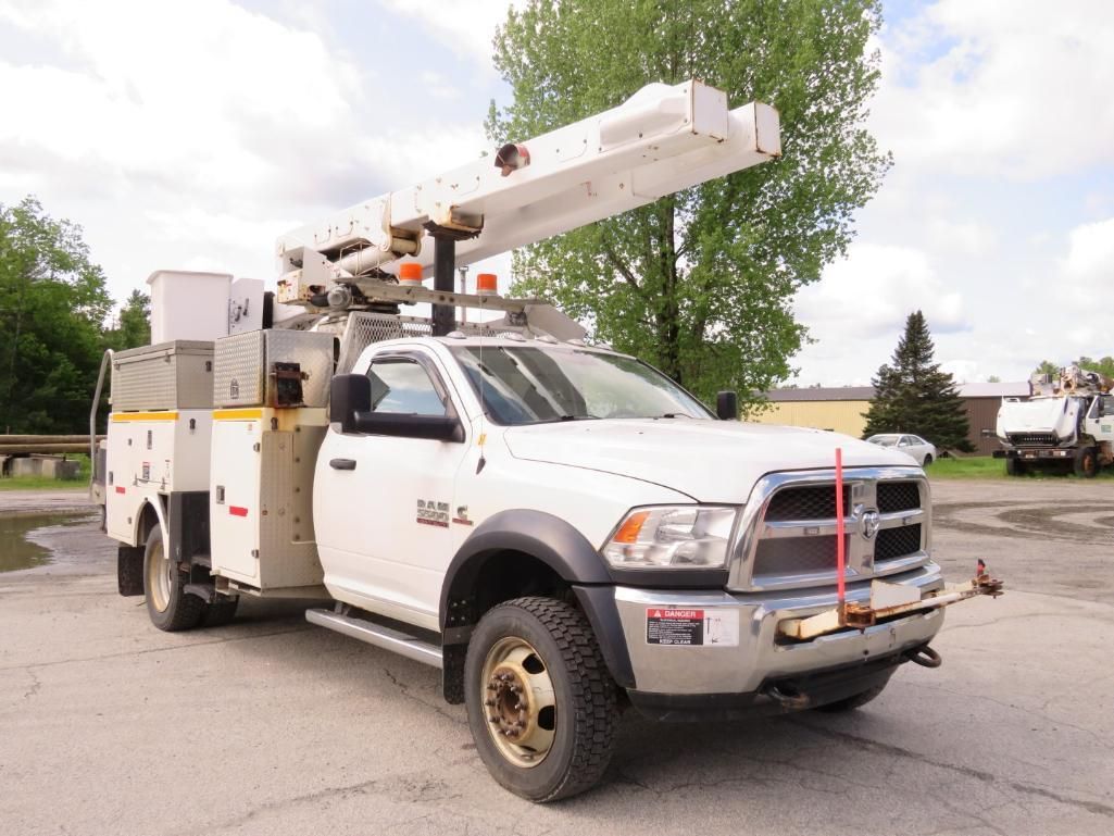 White utility truck with an extended boom in an outdoor setting.