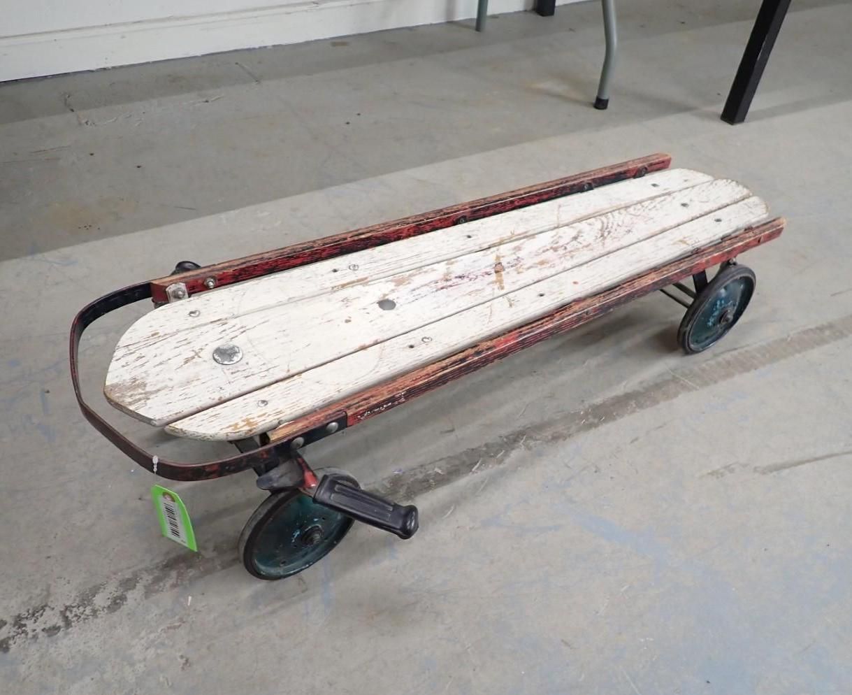 Vintage wooden push scooter with red and white paint and black wheels.