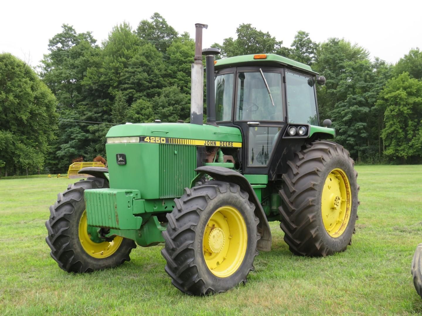 Green and yellow John Deere 4650 tractor on a grassy field with a tree background.