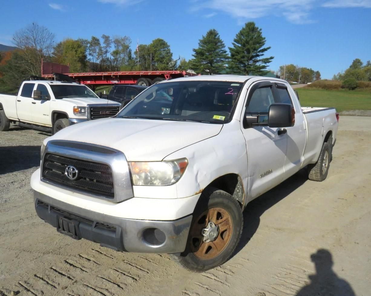 White Toyota Tundra pickup truck with dust on the wheels parked outside on a sunny day.