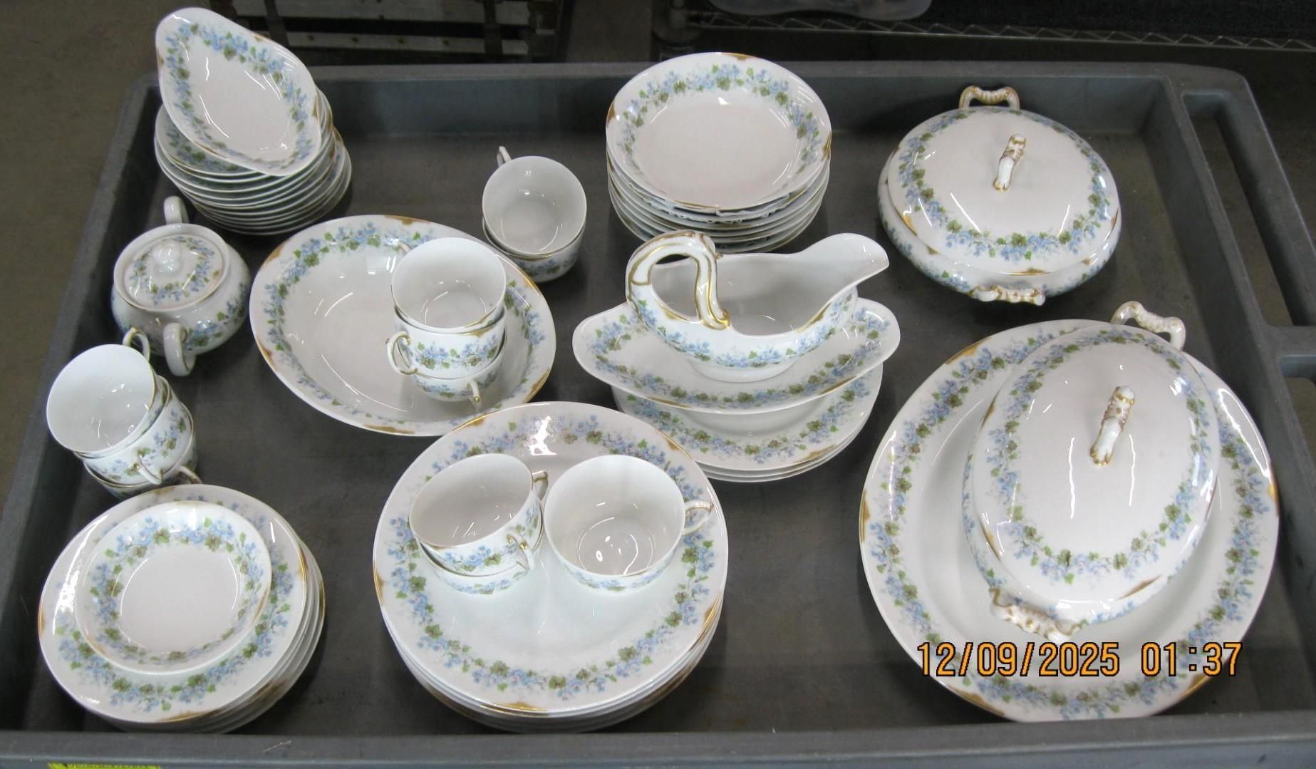 A collection of floral patterned china dishes, including plates, bowls, and serving pieces, arranged in a tray.