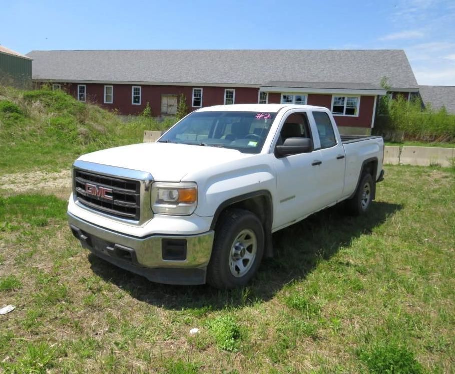 White GMC Sierra pickup truck parked on grass in front of a red building.