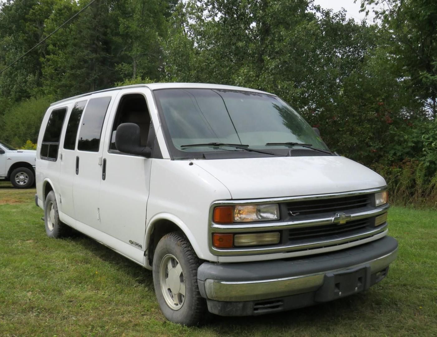 White Chevrolet passenger van parked on grass.