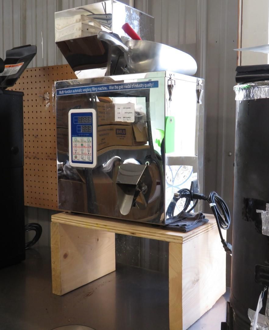 Stainless steel coffee grinder on a wooden stand in a commercial setting.