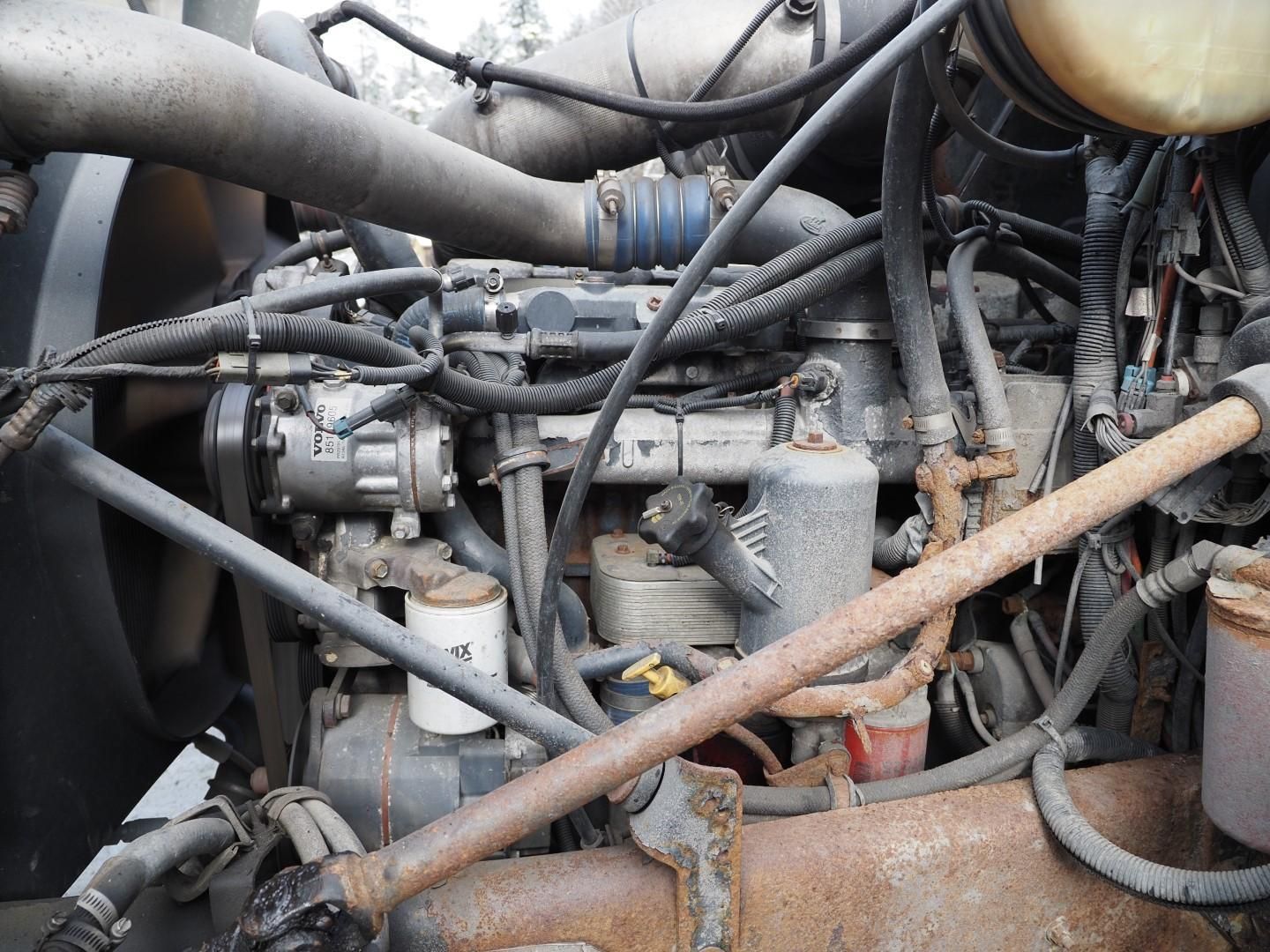 Engine compartment of a truck, with various hoses, wires, and filters.