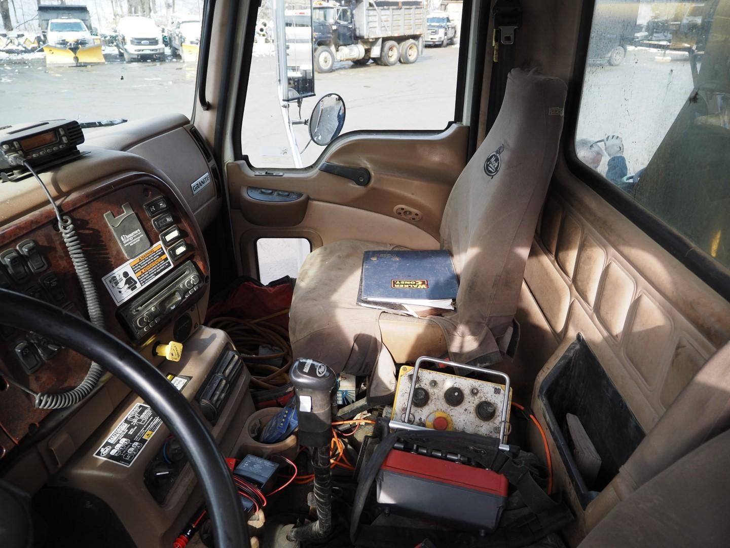 Interior view of a truck cab, showing the driver's seat, dashboard with radio, and various electronic components.