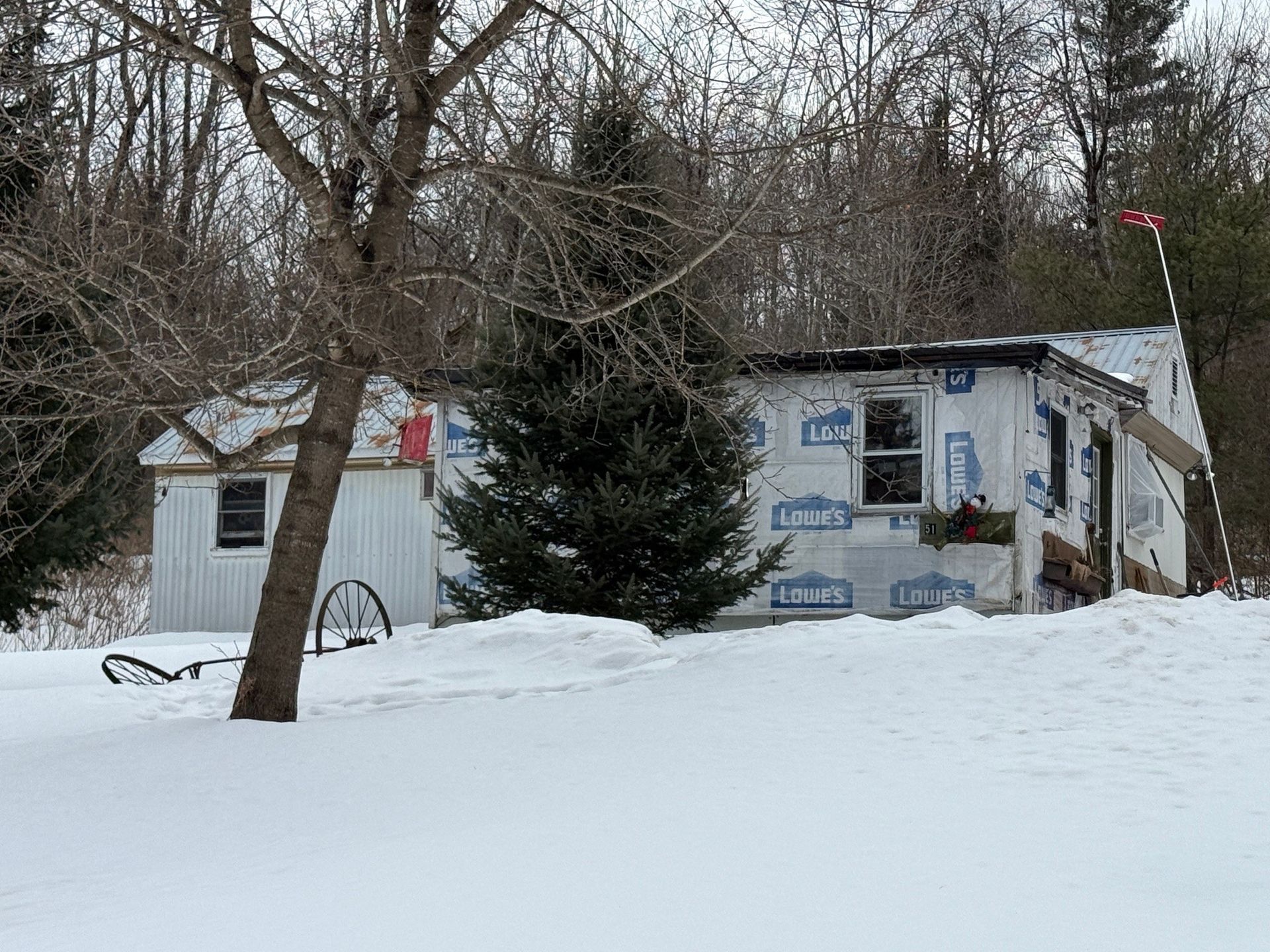 A house surrounded by a snowy landscape and bare trees.