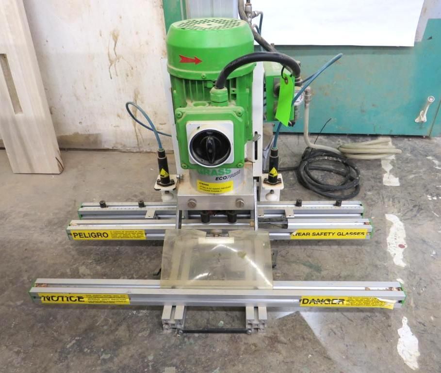 Green and silver door mortiser machine on a concrete floor.