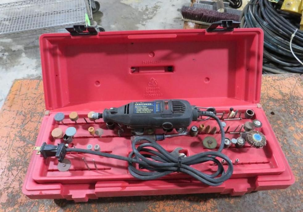 Red toolbox containing a rotary tool and various bits, on an orange surface.