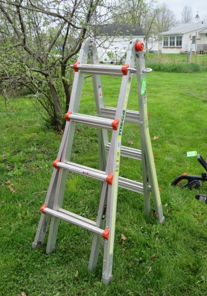 Aluminum multi-position ladder set up on a grassy lawn.