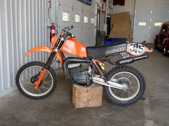 Orange Can-Am motorcycle inside a garage.