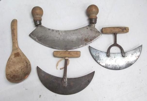 Wooden spoon and three metal mezzalunas with wooden handles on a white surface.