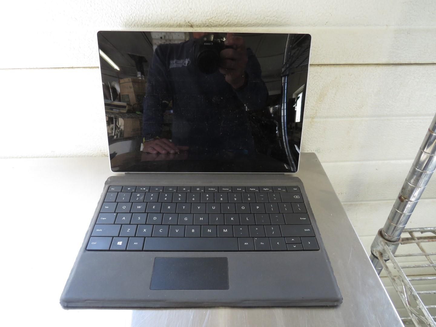 A dark gray laptop computer, sitting on a metal surface.
