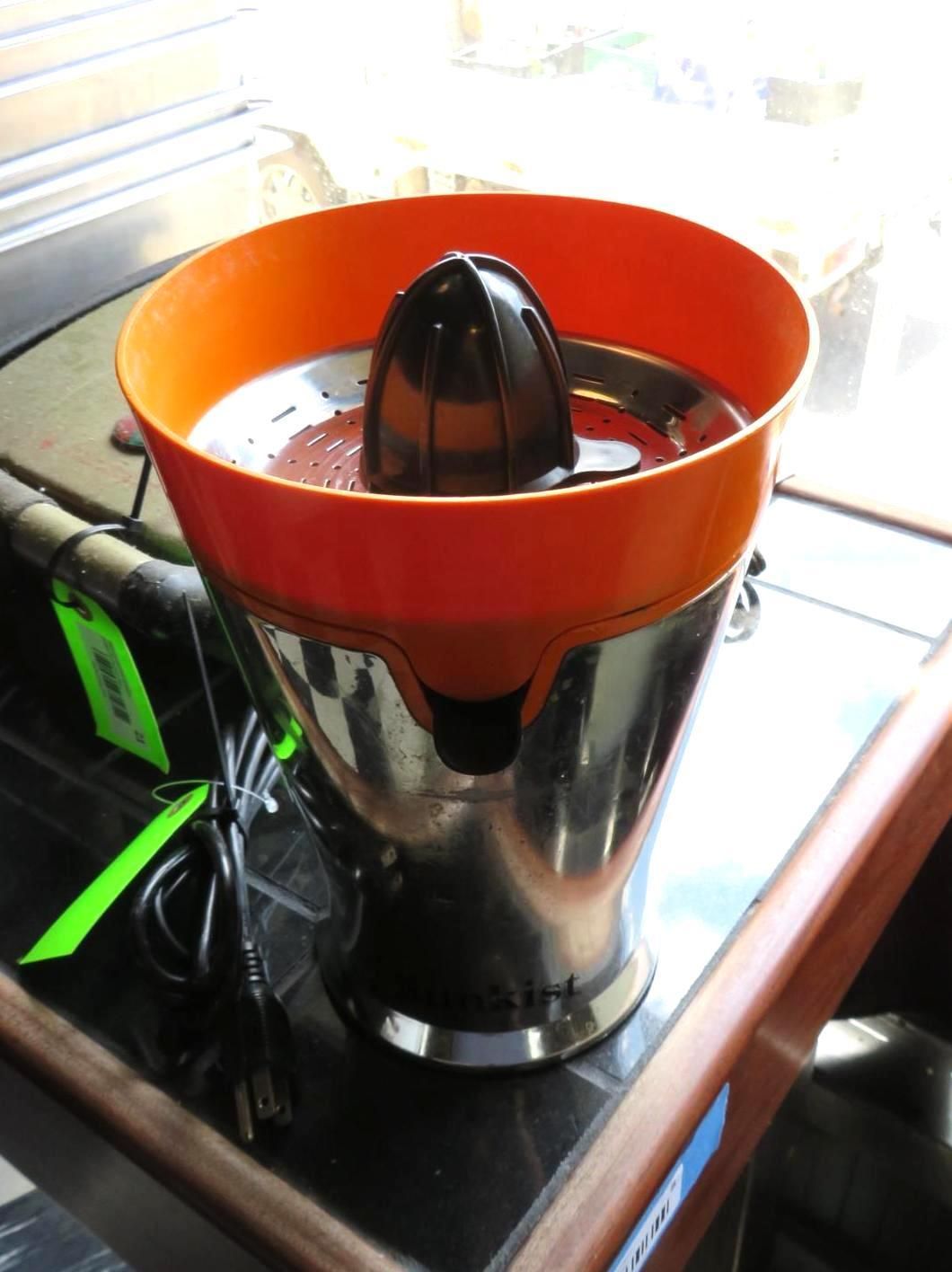 Orange and silver electric citrus juicer on a dark surface.
