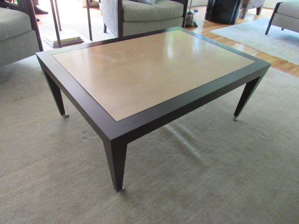 Brown and beige rectangular coffee table with dark brown frame and legs on a light carpet.