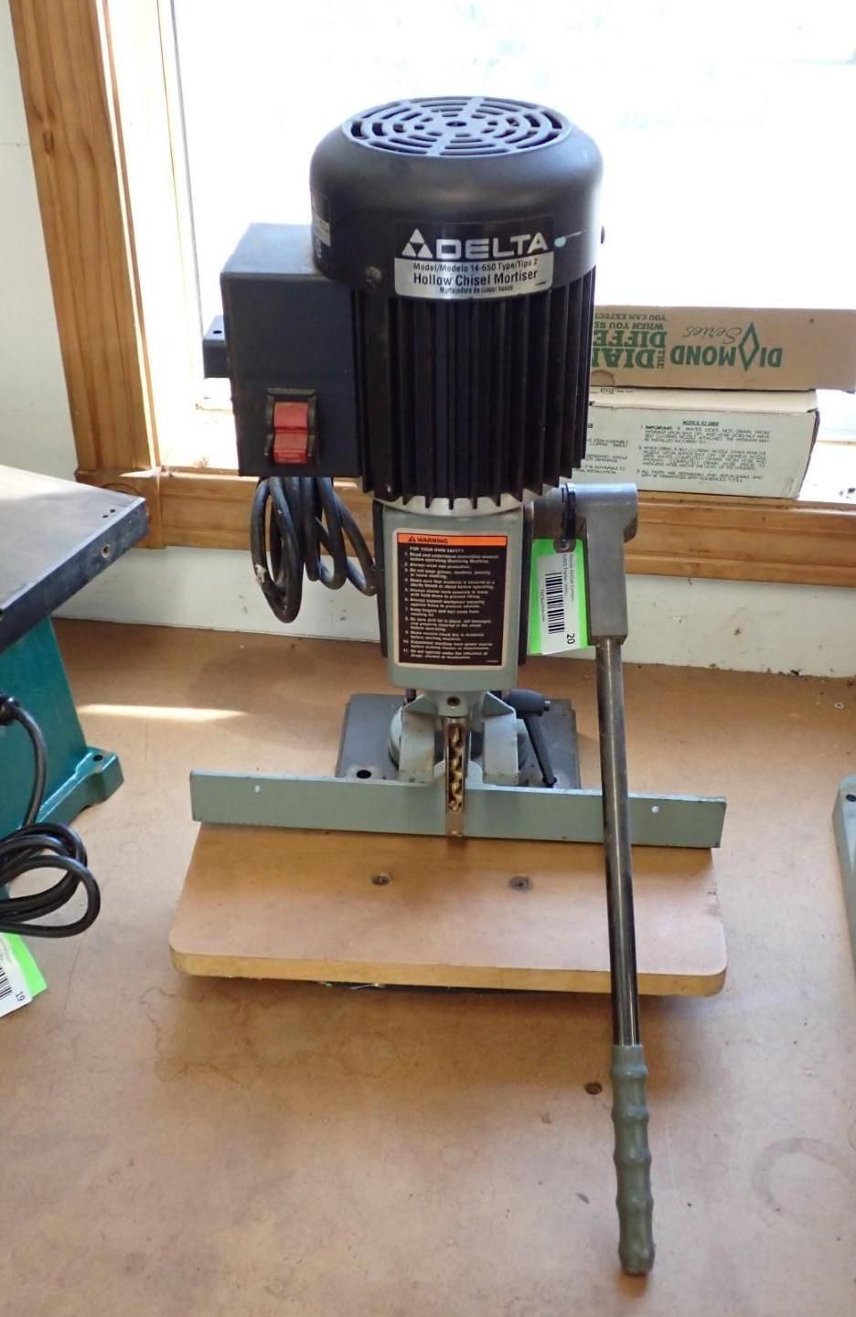 Industrial mortise machine with a motor, handle, and a wooden base.