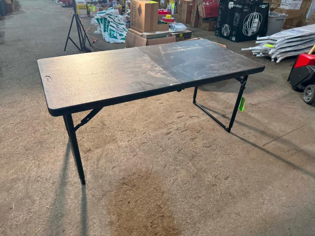 Black folding table with dark gray top in an industrial setting.