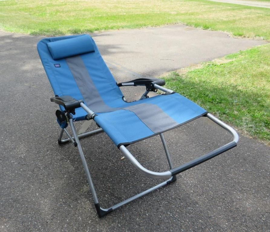 Blue and gray outdoor folding recliner chair on a paved surface with grass in the background.