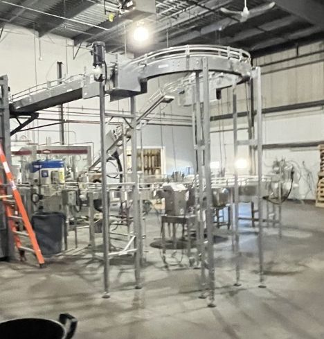Industrial food processing machinery in a factory setting; a conveyor belt system.