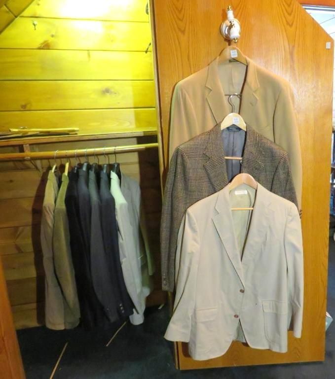 Clothes hanging in a closet. Suits and jackets in neutral colors.