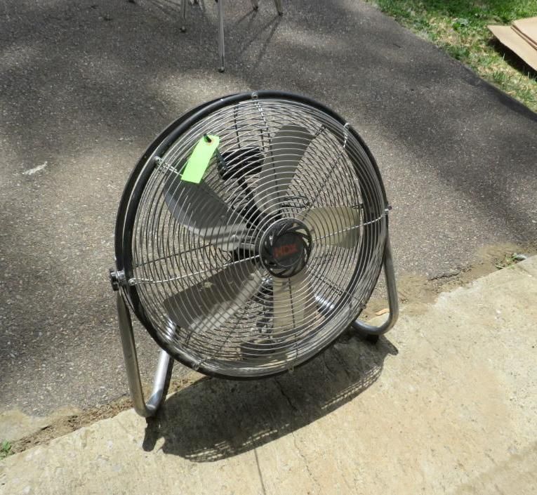 Large black and silver metal industrial fan on a concrete surface.