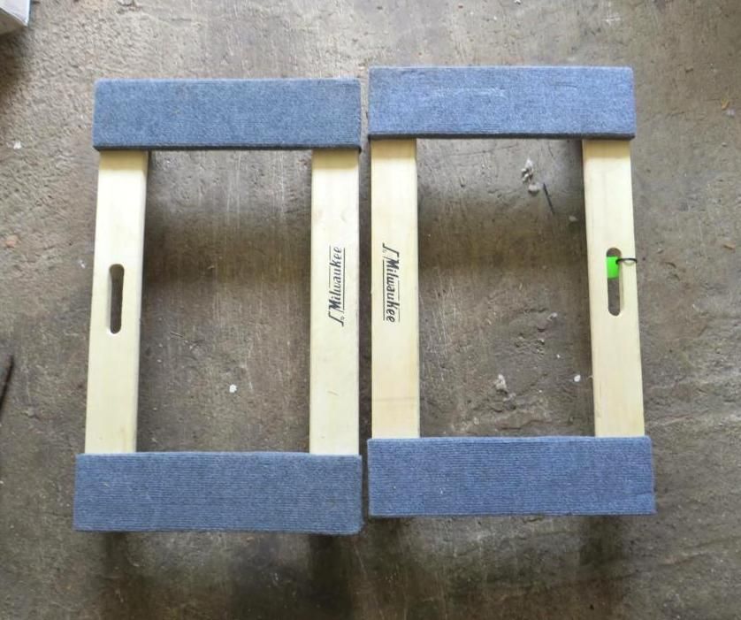 Two wooden boat dollies with blue padded tops.