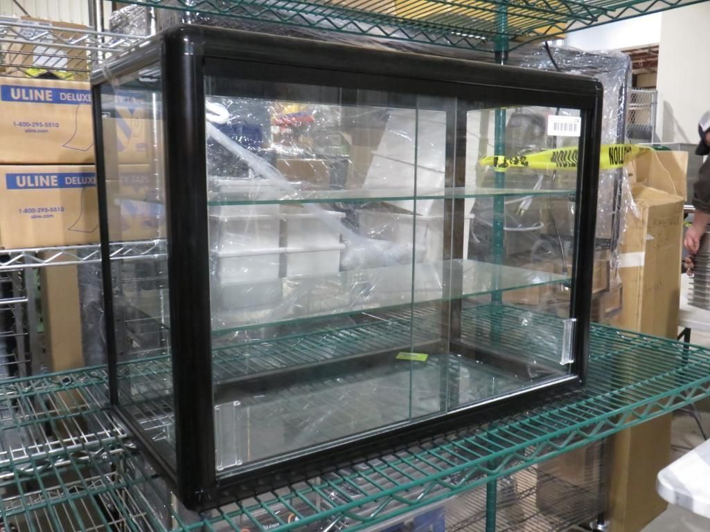 Glass display case with black frame, three shelves, on a metal rack.