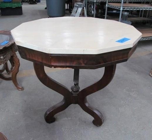 Octagonal table with light top, dark wood base, in a room.