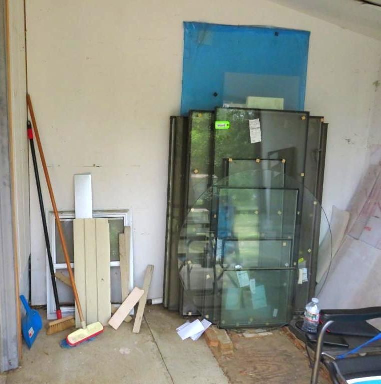 Stacked glass panes, construction materials, and cleaning supplies.