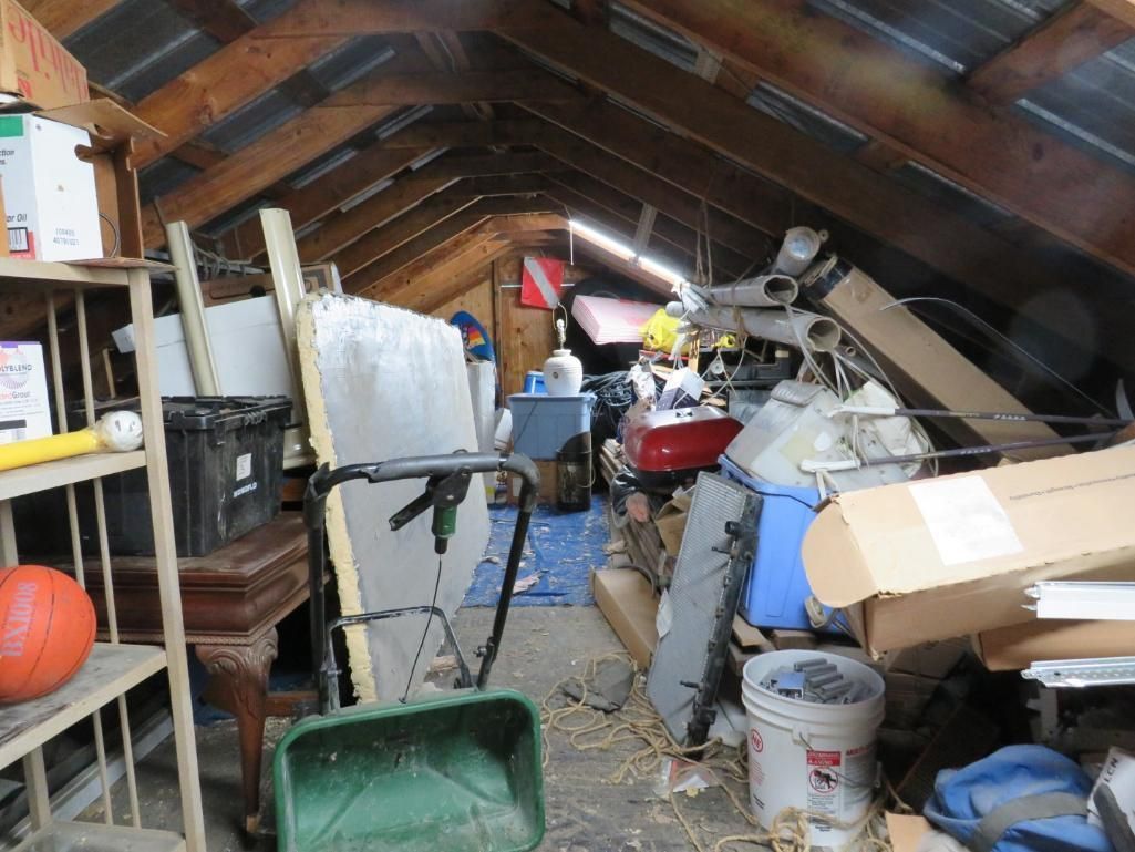 Attic with various items: shelves, boxes, tools.