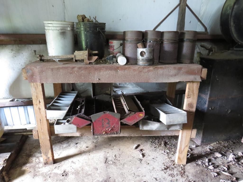 Wooden workbench with tools, materials, and containers in a workshop setting.