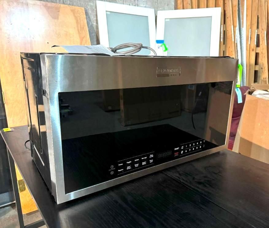 Stainless steel Whirlpool microwave on a dark table, with glass door and control panel.
