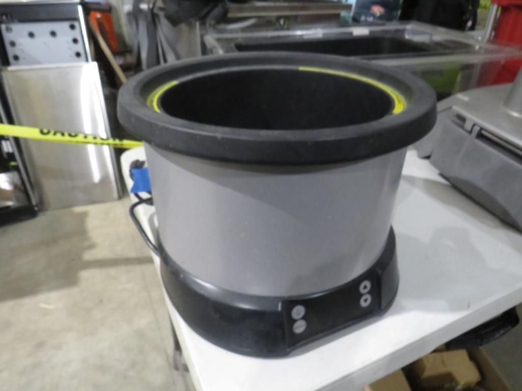 Gray and black cylindrical container with a yellow inner rim and buttons on the base.