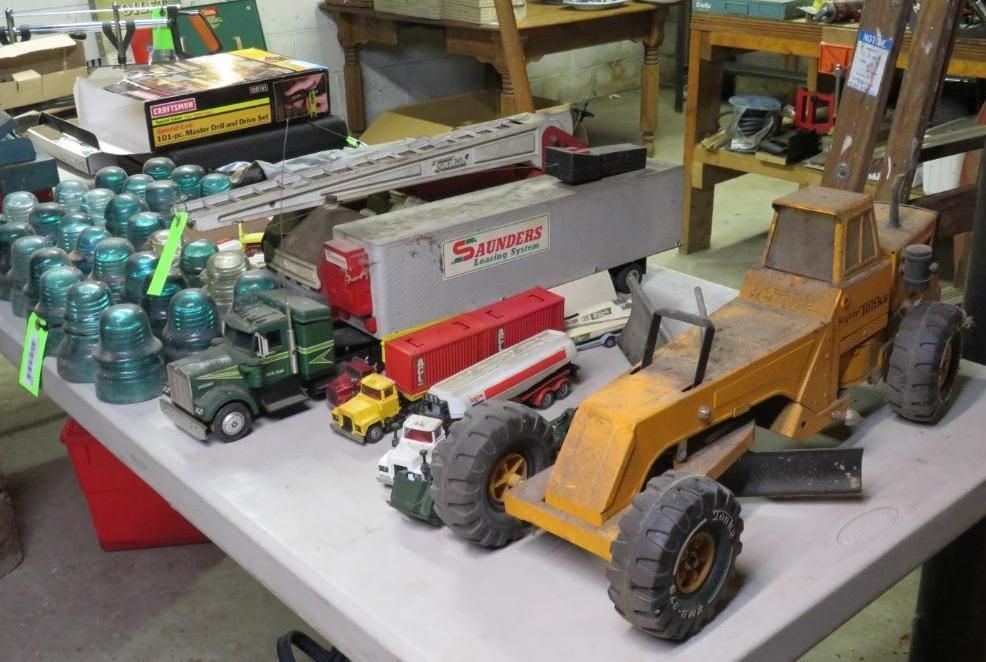 Toy trucks, train cars, and glass insulators on a table at a sale.