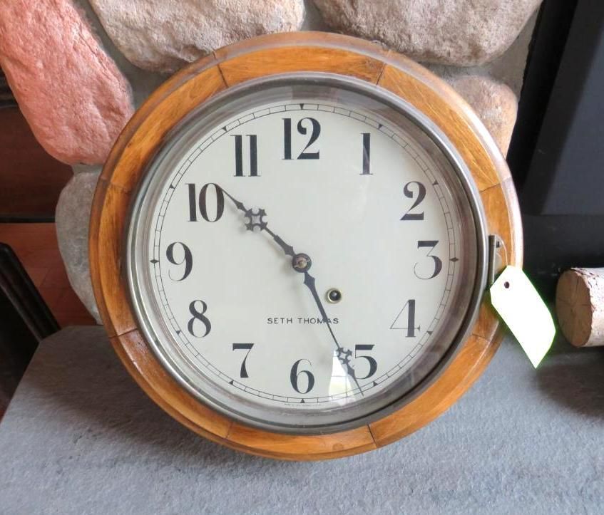 Wooden-framed wall clock with light-colored face, black numerals, and hands.