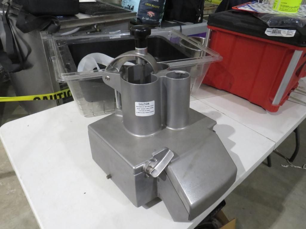 Stainless steel commercial food processor on a white table.