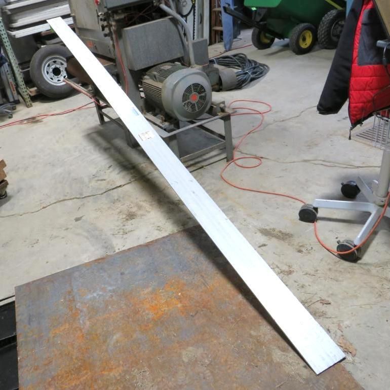 Aluminum strip resting on a metal plate. Workshop setting.