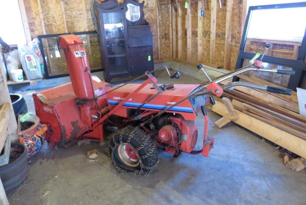 Red snowblower with chains in a garage.