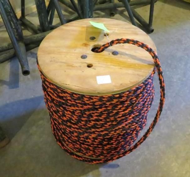 Spool of orange and black braided rope on wooden reel.
