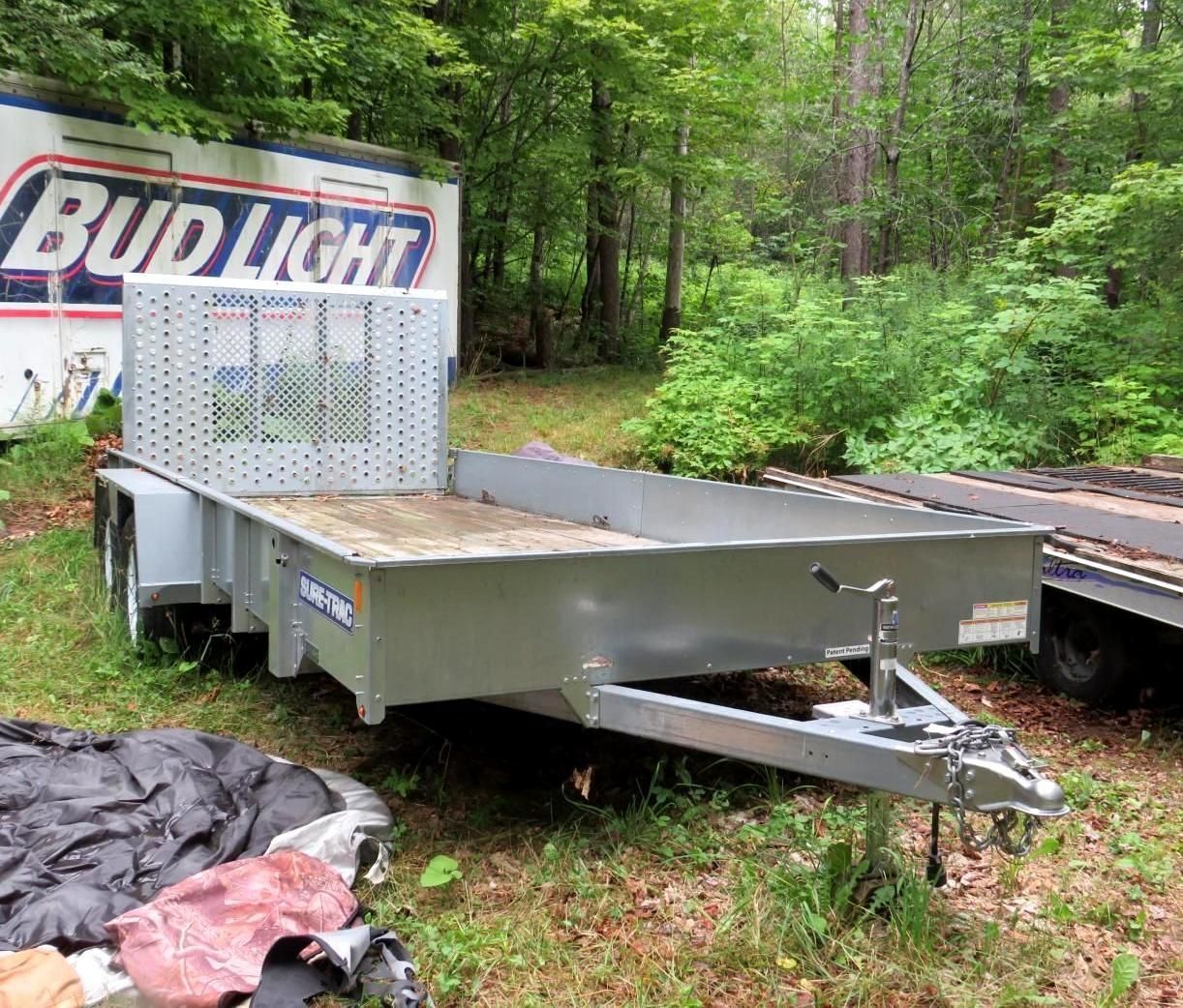 Gray utility trailer in grassy setting.