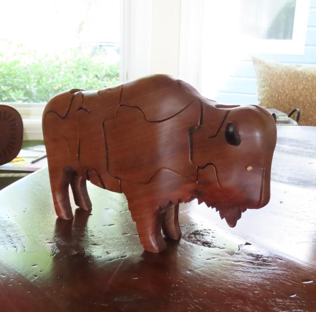 Wooden bison puzzle on a polished table, brown with visible seams, natural light.