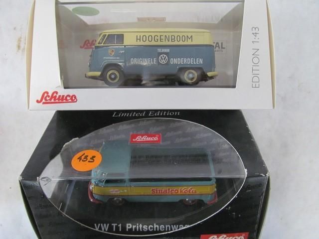 Two model VW T1 vans in boxes. One light blue, yellow, and white. The other a similar color palette, flatbed style.