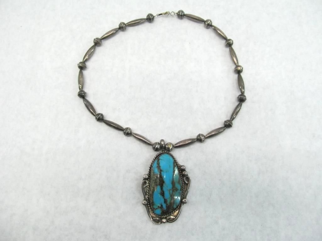 Silver necklace with turquoise pendant.