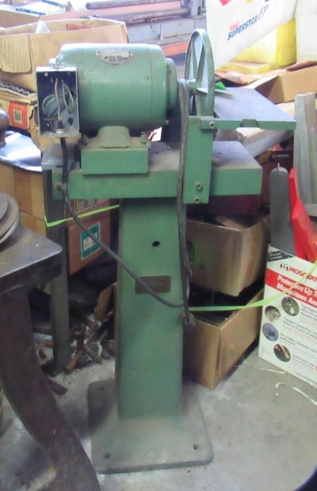 Green belt sander machine in a workshop.