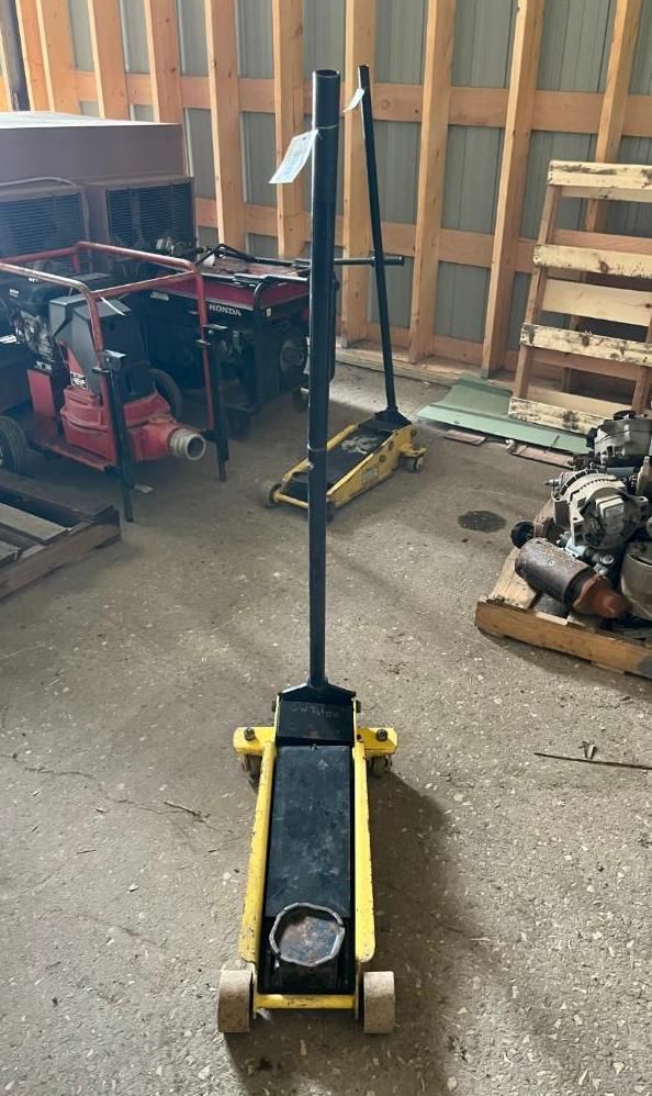 Yellow and black floor jack in a workshop setting.