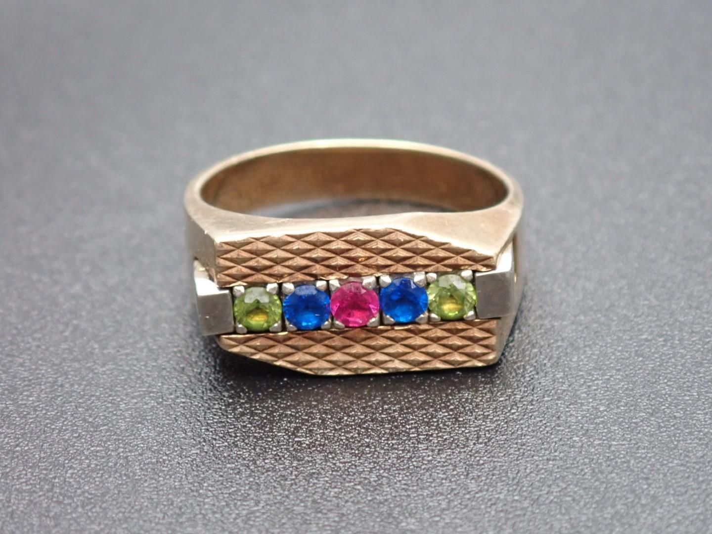 Gold ring with a row of five gemstones: green, blue, pink, blue, green.